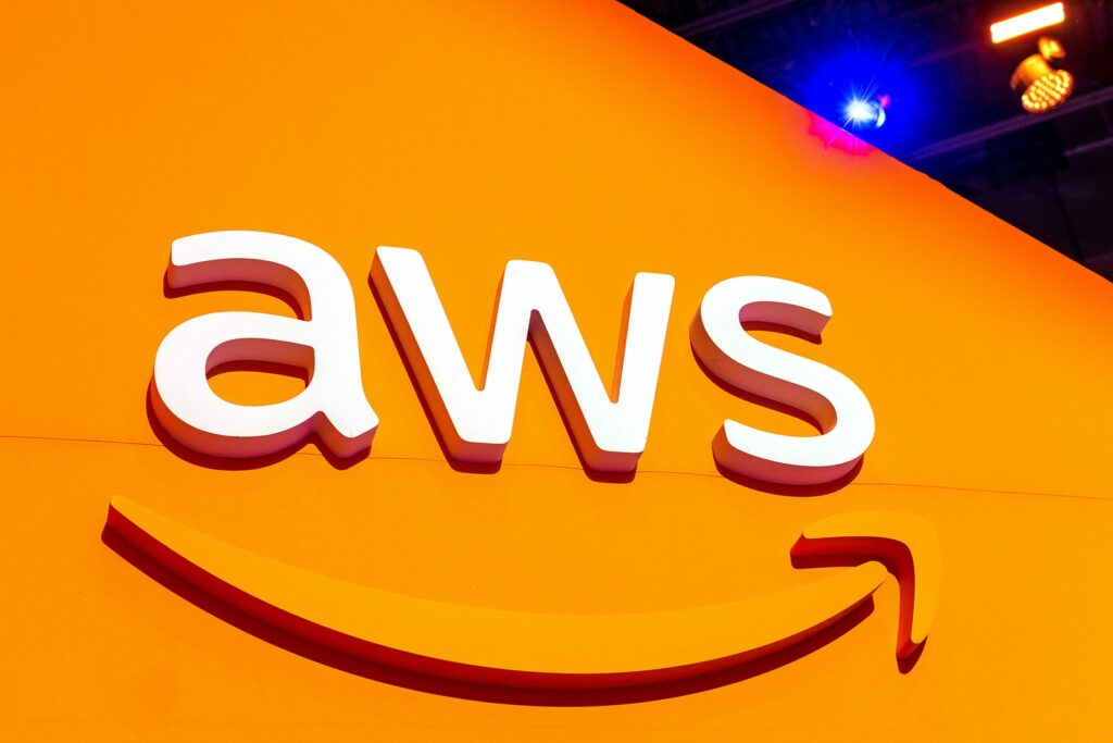 AWS logo on an orange wall with blue light shining over the top corner