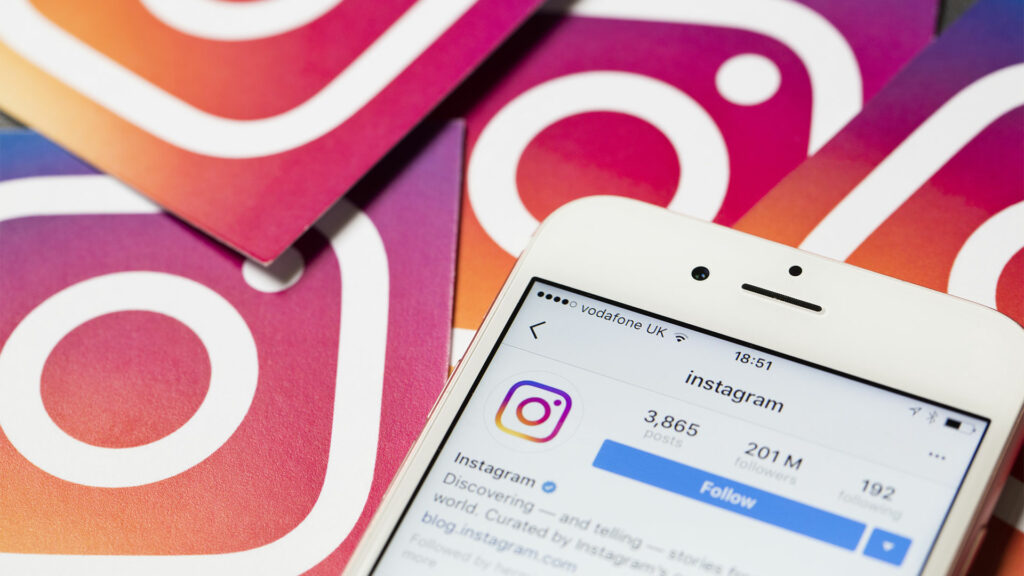 Smartphone on Instagram app screen with Instagram logo stickers in background