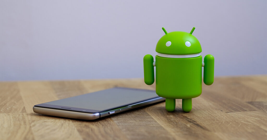 Android icon next to smartphone on a wooden table