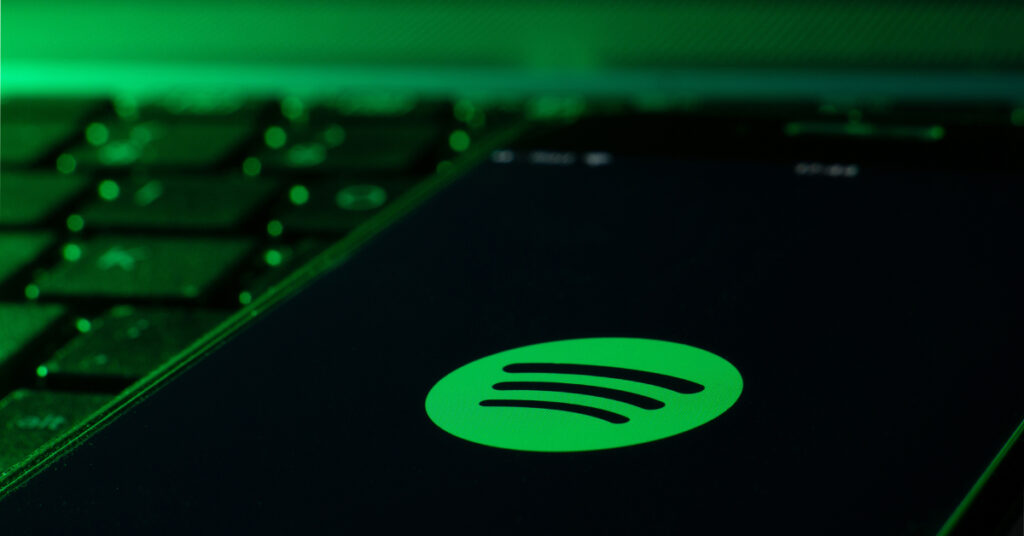 Spotify logo on smartphone resting atop laptop