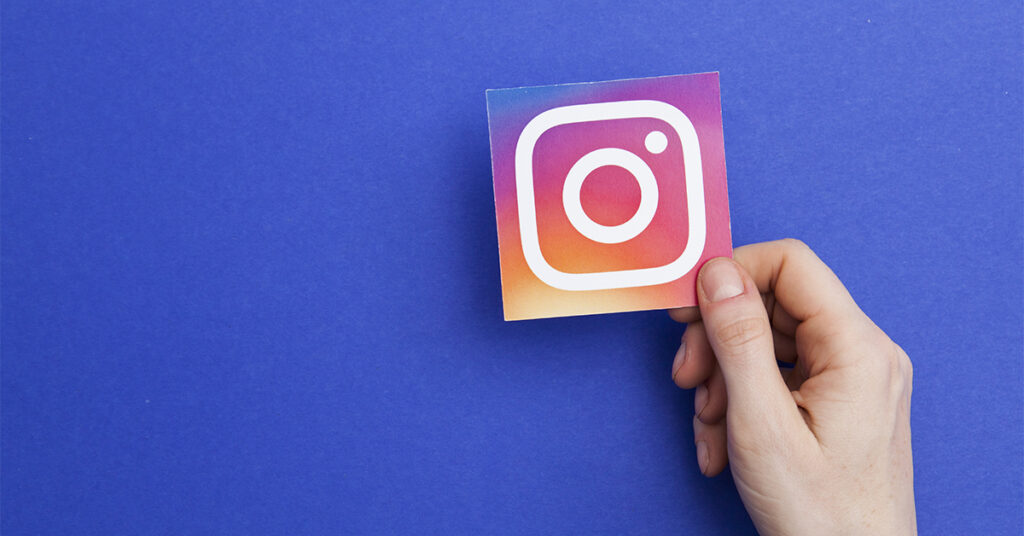 Person holding Instagram logo against blue background