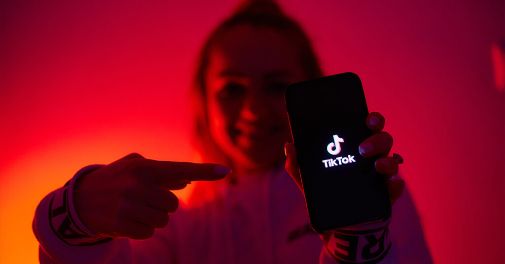 Person holding cellphone with TikTok logo on screen
