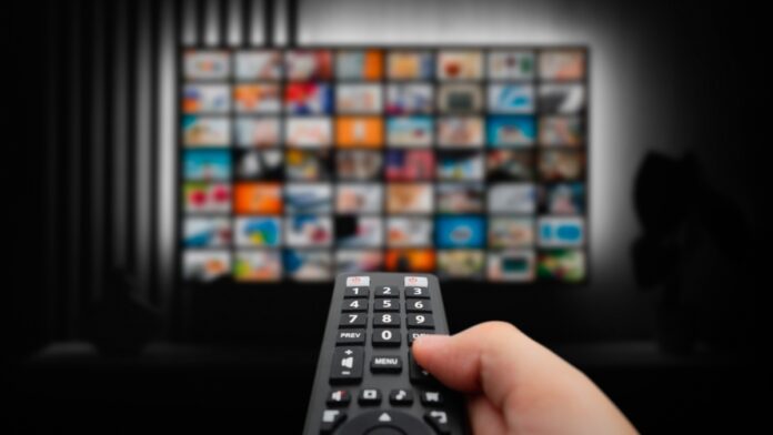 Closeup of a person using their smart TV remote scrolling through streaming shows.